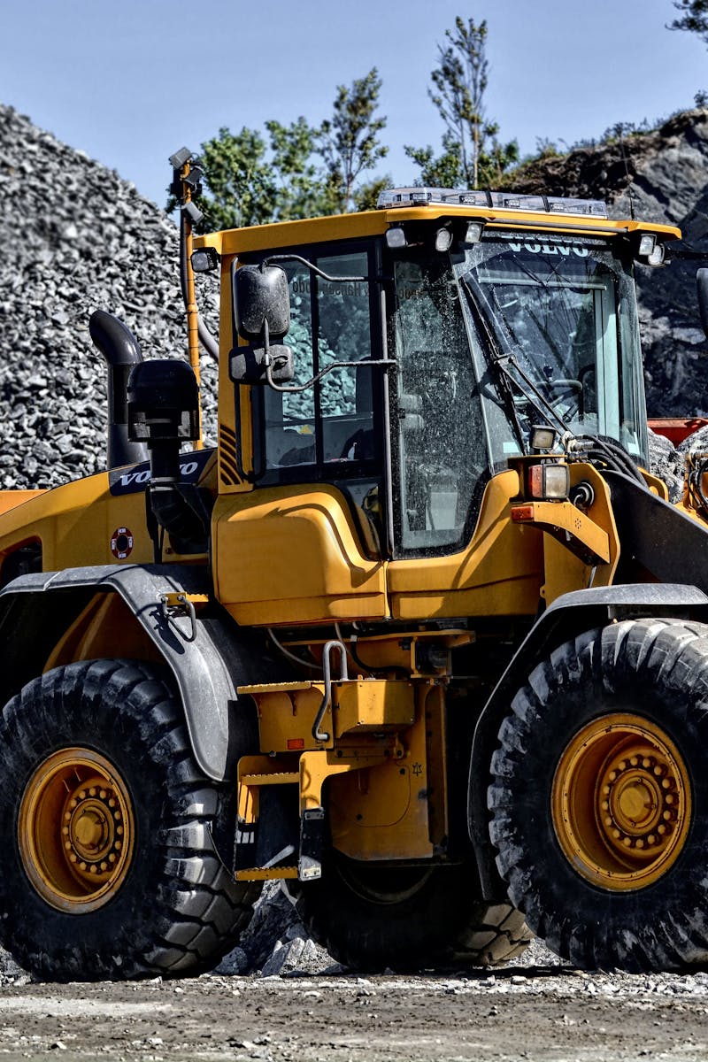 Powerful yellow construction loader moving gravel in an industrial quarry site.